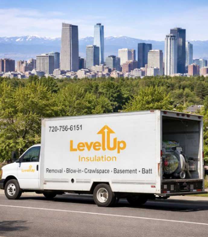 Level Up Insulation Co. service truck driving in Denver, Colorado with the downtown skyline and Rocky Mountains in the background.